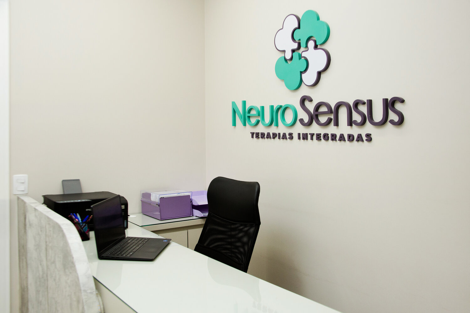 Recepção da Neuro Sensus com a logo da clínica na parede